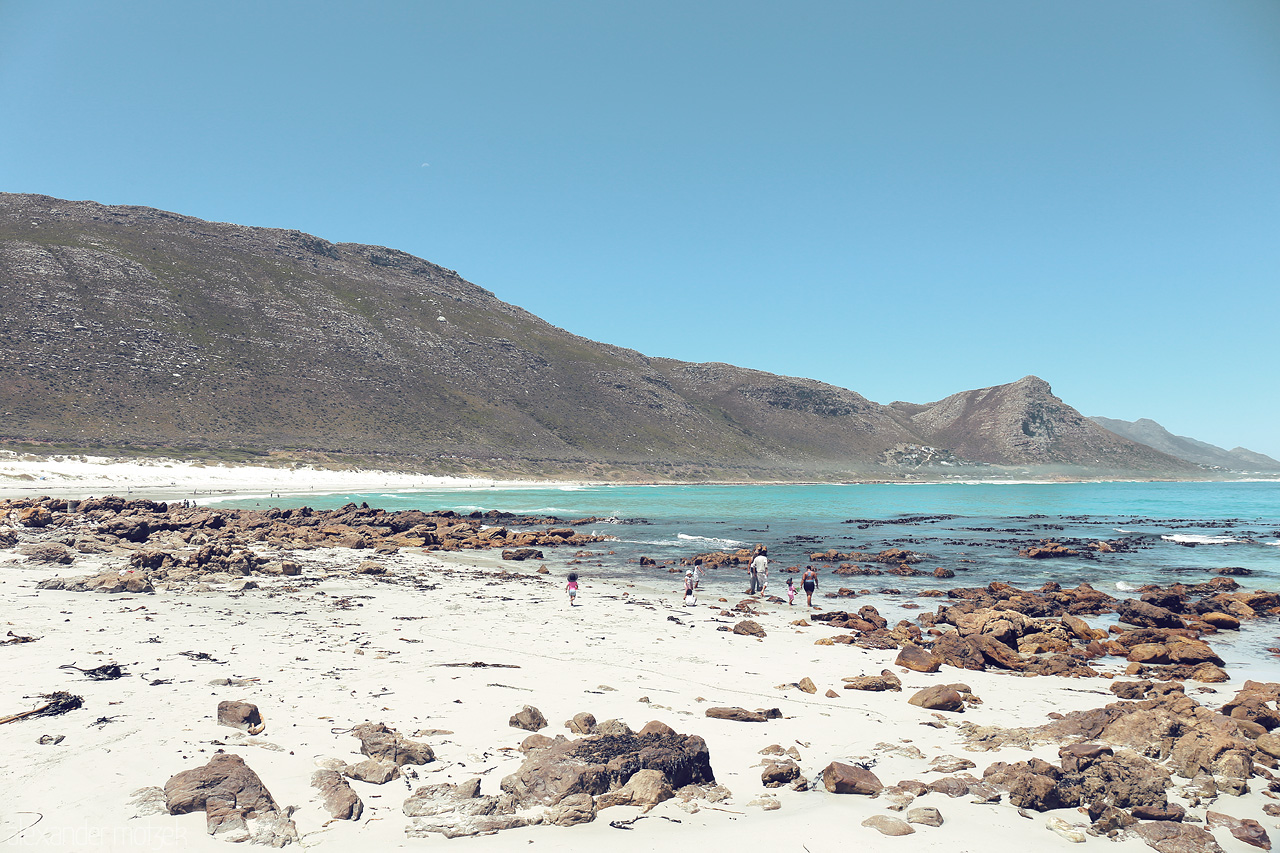 Breezy Boulders of Table Bay Foto von Explore Cape Town's rugged coastline where the mountains meet the turquoise sea, dotted with boulders and kissed by the clear, sunny skies.